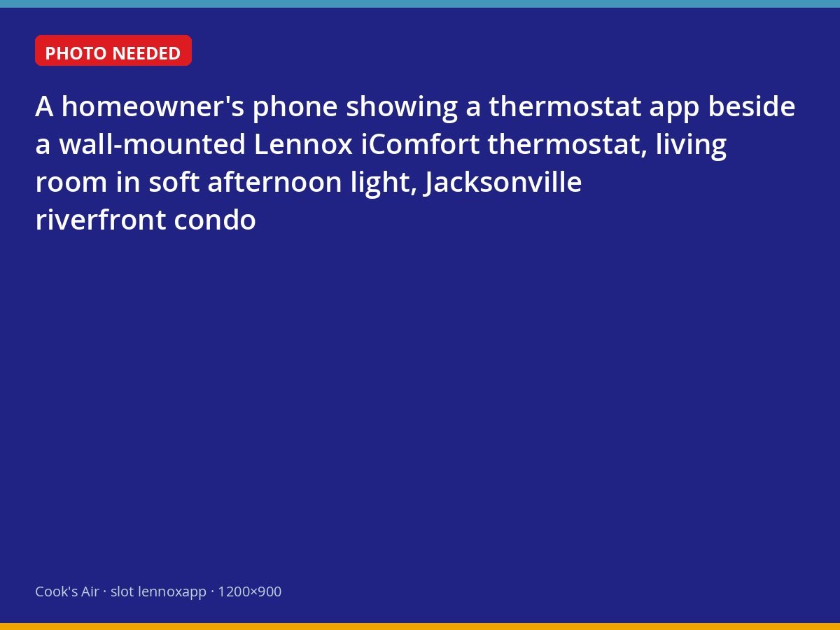 Smart thermostat on a wall with its companion app open on a phone